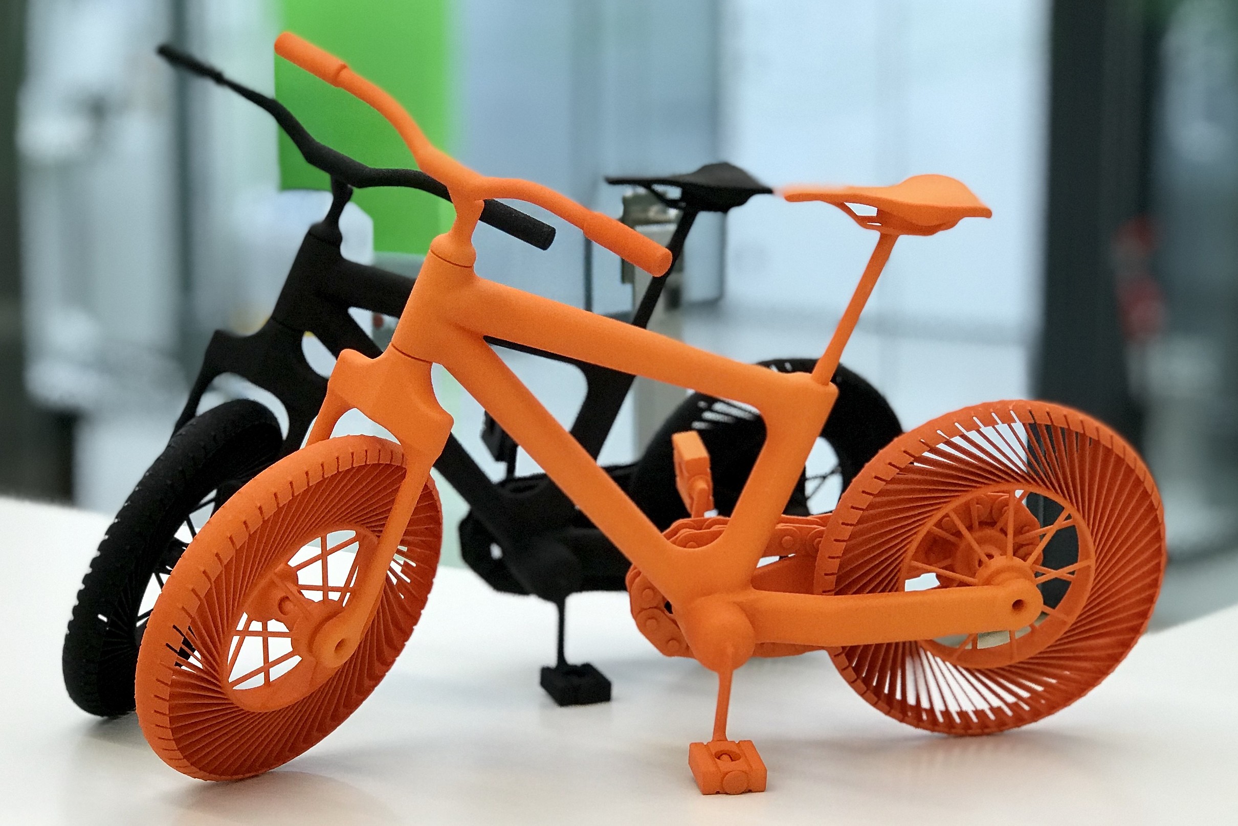 zwei SLS-Teile, aussehend wie kleine Fahrräder, in orange und schwarz 