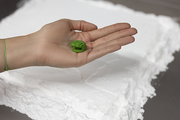 Das Bild zeigt eine kleine Spulenkapsel in grün in perfekter Ausführung welche nicht größer ist als ein Fingernagel