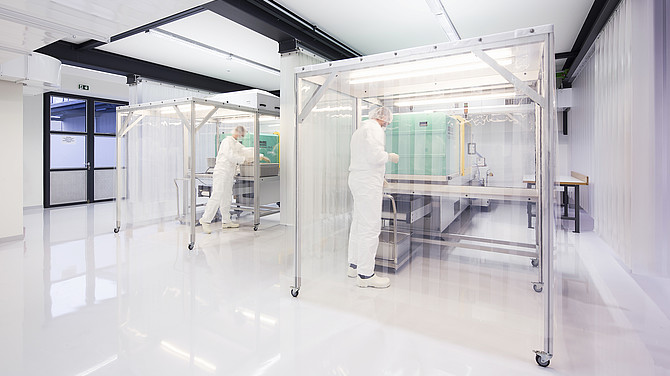 Das Bild zeigt zwei 1zu1mitarbeiter in Schutzkleidung in der 1zu1reinraumfertigung für die Herstellung von keimfreien und sterilen Kunststoffteilen.