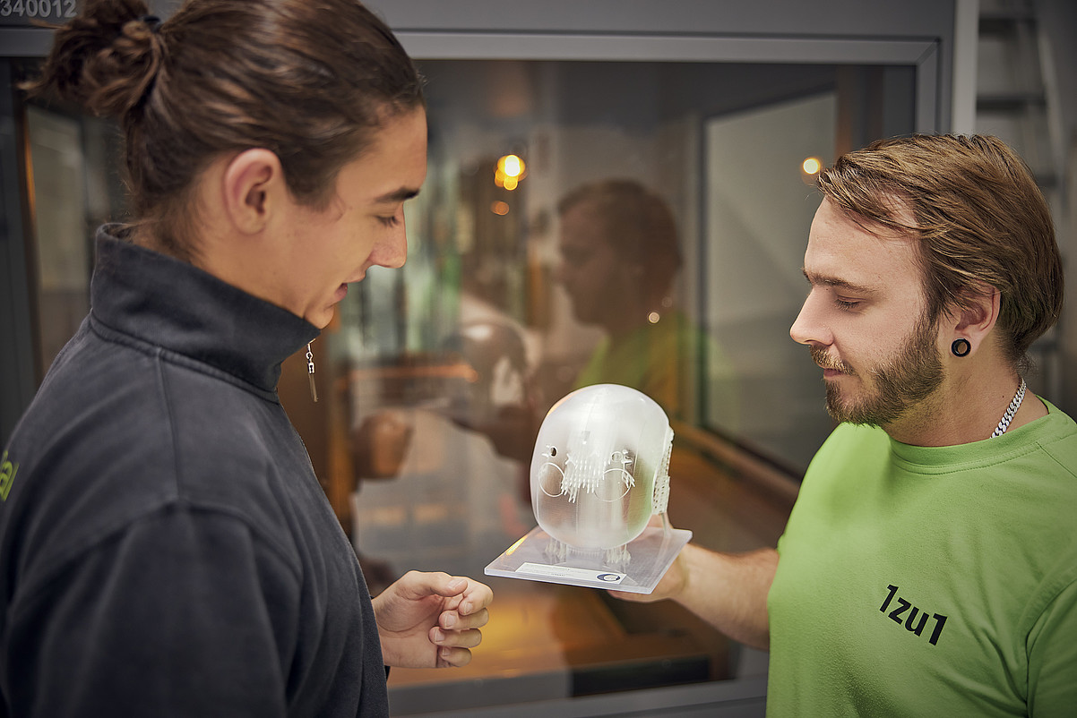 SLA Fertigungsleiter Timmy Eigster mit Raphael Fend bei der Ansicht eines Kunststoffbauteiles aus dem SLA Drucker