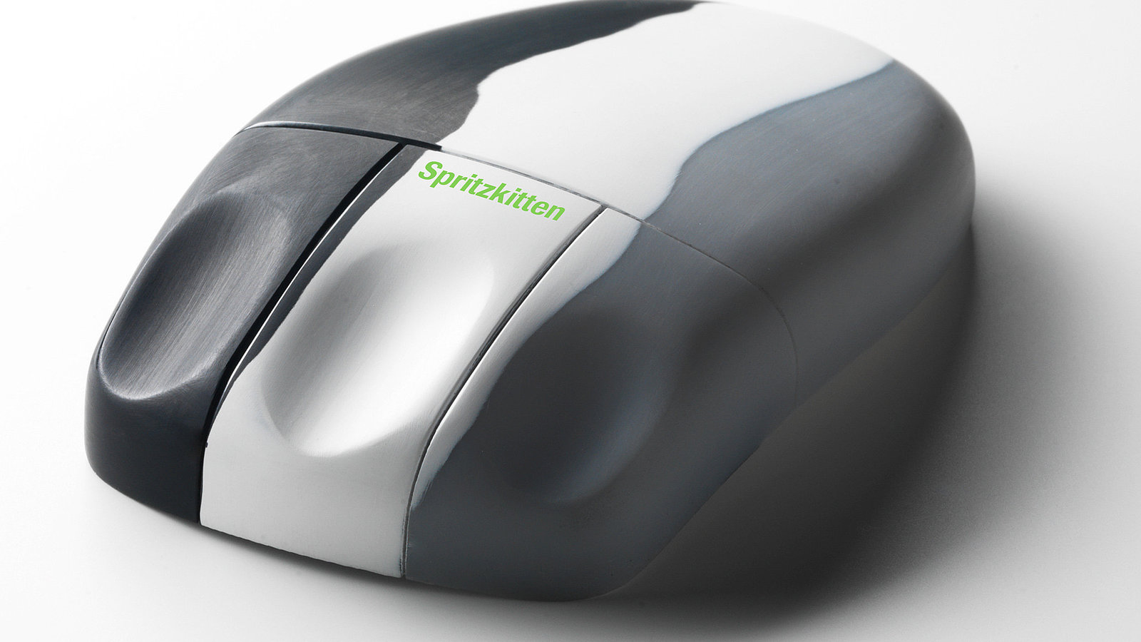 Das Bild zeigt eine schwarz/weiß/grau Maus mit grüner Aufschrift "Spritzkitten". Spritzkitten ist eine Art von Oberflächentechnik welche Kunststoffteile an Ihre Perfektion bringt.